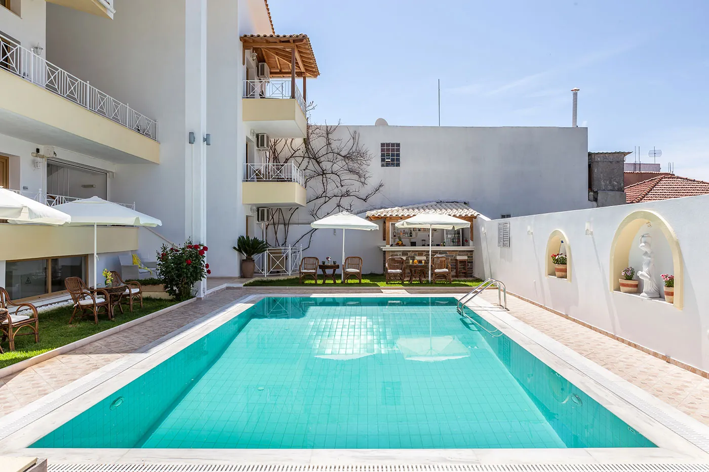The turquoise pool, its umbrellas and the pergola beside the building