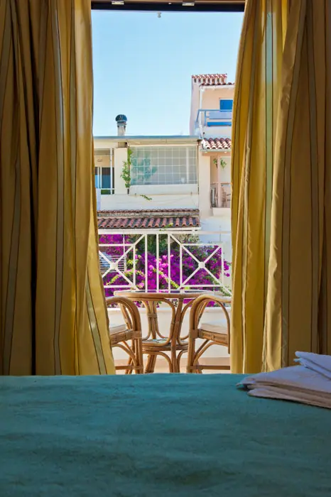 Yellow curtains open onto a flowered balcony