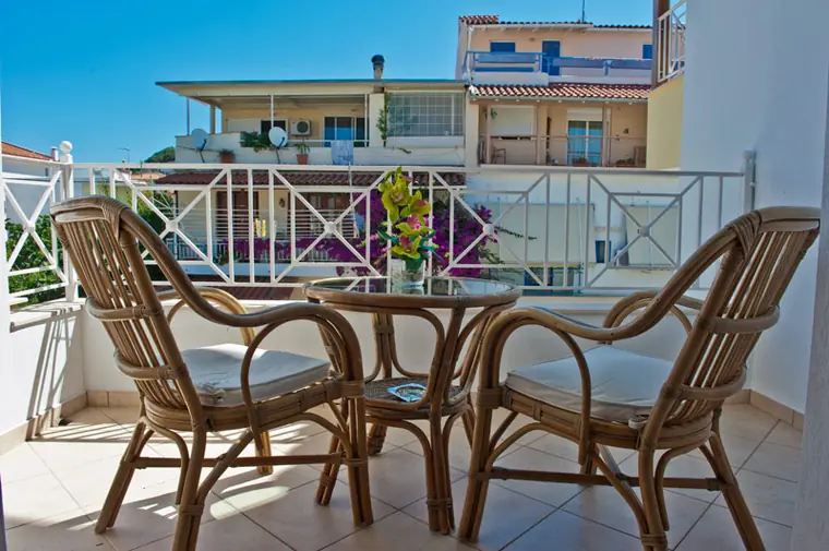 Cane chairs on a balcony above the neighbouring rooftops