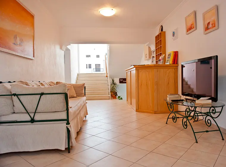 A living area with sofa, TV and stairs to the upper floor