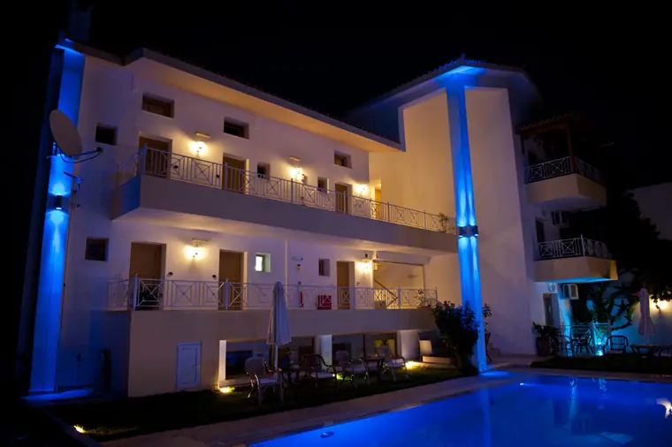 The building lit in blue at night beside the pool