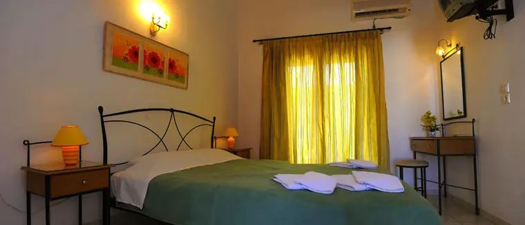 A bed with a green cover under yellow curtains